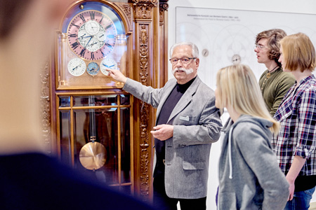 Gästeführer stellt einer Besuchergruppe die Goertz-Uhr vor