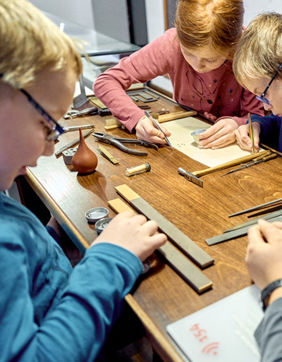 Kinder probieren sich am Uhrmachertisch